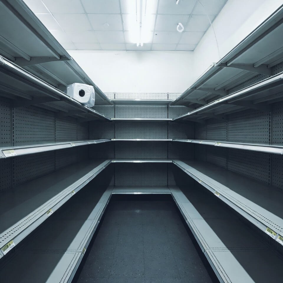 Empty big-box store aisle with one lonely toilet paper pack high up