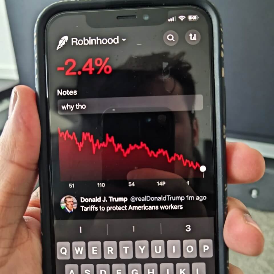 Robinhood app screen with -2.4% dip and defeated face reflection