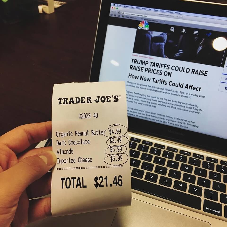 Blurry Trader Joe's receipt with higher import prices next to CNBC tariff article