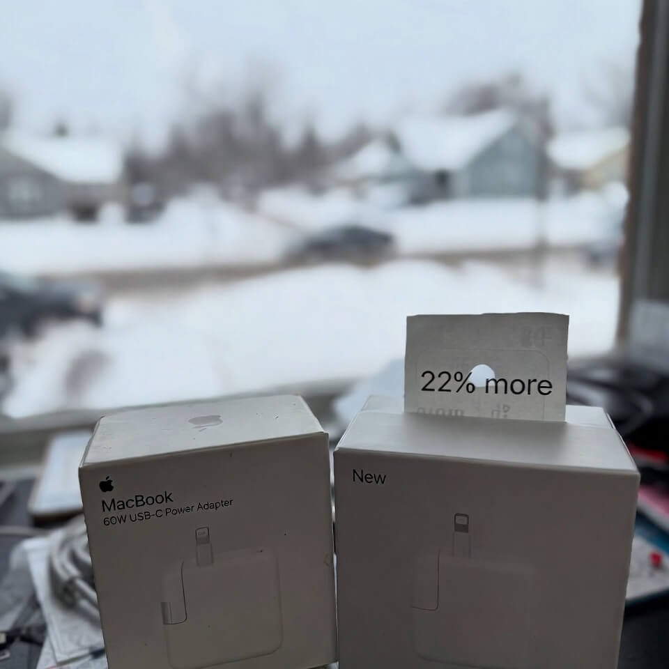 Messy desk with old and new MacBook chargers, snowy window background